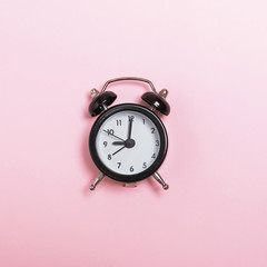 Small alarm clock isolated on pastel pink background