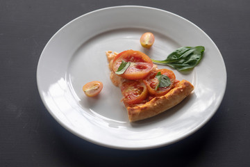 Slice of pizza margherita on a white plate.