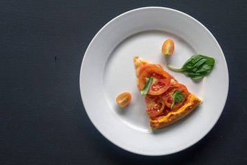 Slice of pizza margherita on a white plate.