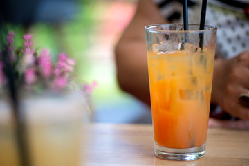 Glass of alcoholic tequila sunrise or campari and grenadine cocktail with juice in restaurant of bar. Concept of luxury holidays and vacation. Woman holding full glass of cold, refreshing beverage  