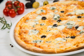 4 cheese pizza on white wooden background. Background decorated with vegetables