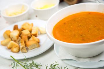 fish soup mashed potatoes with crackers on a white wooden background. The background is decorated with vegetables.