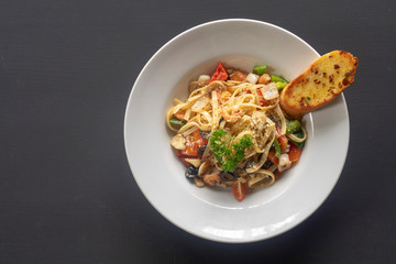Seafood pasta on a white plate on a dark background