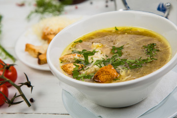 onion soup in a white plate with crackers on a white wooden background. The background is decorated with vegetables.