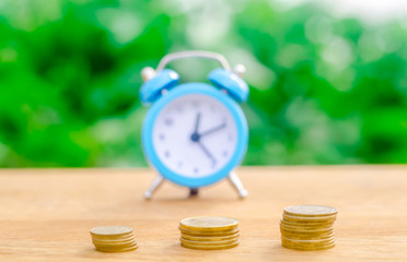 Alarm clock and money on green bokeh background. The concept of Time is money. Business financial ideas. Saving. Financial investments, revenue increase, budget management. Soft selective focus