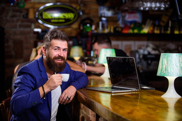 Man bearded businessman sit bar counter with laptop and cup of coffee. Create content web blog. Manager create post enjoy coffee. Hipster freelancer work online drinking coffee. Coffee break concept