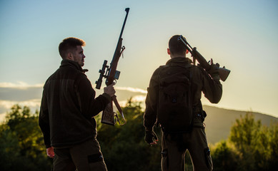 Fototapeta premium Hunters friends gamekeepers with guns silhouette sky background. Hunters rifles nature environment. That was great day. Finish hunting season. Enjoy sunset in mountains. Hunters friends enjoy leisure