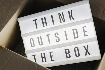 Think outside the box message on lightbox coming out of a parcel