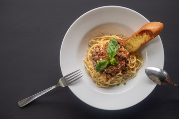 Pasta bolognese on a white plate on a dark background