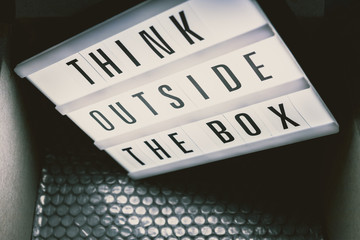 Think outside the box message on lightbox coming out of a parcel
