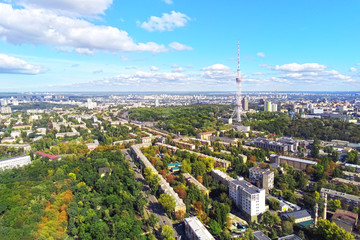 Aerial view of Kiev city streets with park and high steel TV tower against blue sky om bright sunny day