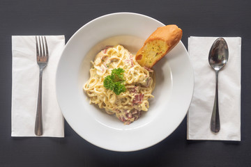 Carbonara paste on a white plate on a dark background