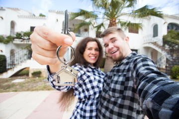 Obraz premium Property, real estate and rent concept - Happy smiling young couple showing a keys of their new house