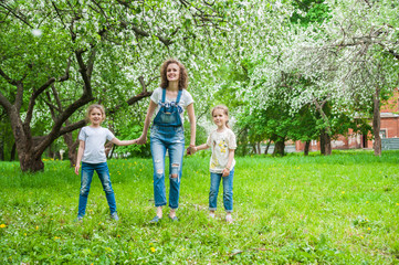 Obraz premium Family walks in blooming apple orchard in spring