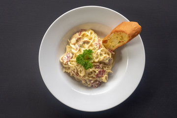 Carbonara paste on a white plate on a dark background