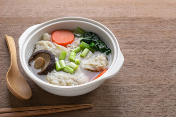pork wonton soup with vegetable in a ceramic bowl on wooden table.  asian food concept.