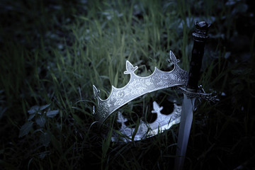 mysterious and magical photo of silver king crown and sword in the England woods or field...