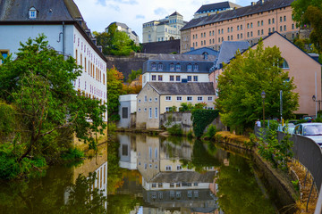 Fototapeta na wymiar Alzette river crossing the old town of Luxembourg, Europe, with colorful typical houses and wall at the background