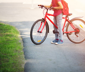Fototapeta na wymiar Child with rucksack riding on bike in the park near school