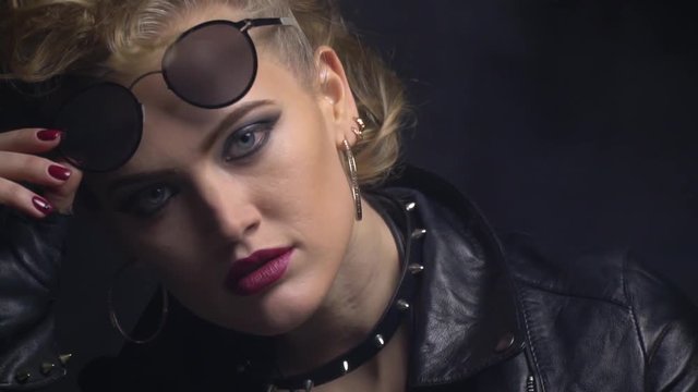 Young woman posing in sunglasses, blode curl on her forehead