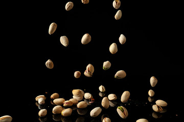 Falling pistachio nuts on dark background