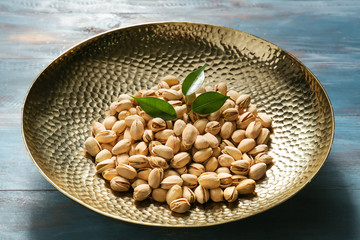 Bowl with tasty pistachio nuts on table