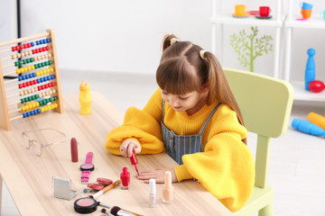 Cute little fashionista with nail polish at home