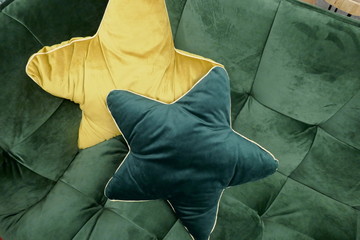 two cuddly yellow star-shaped pillows on a green sofa 