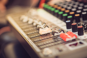 The hand over adjusting knobs on a professional audio mixer for sound mixer control. Selective focus.