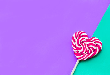 Red valentine day hearth shape lollipop on the violet and green background