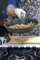 Chef cooks meat in a pan on the fire