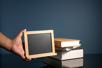 Hand holding blackboard and stalking books with low light