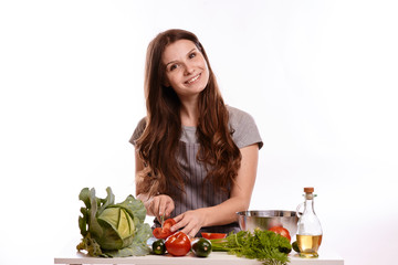 happy adult woman with various fresh vegetables on kitchen table looking at camera