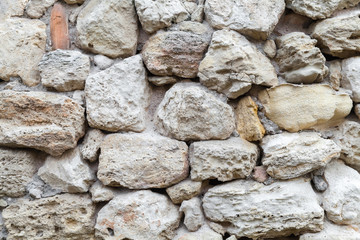 Old gray rough stone wall. Close-up