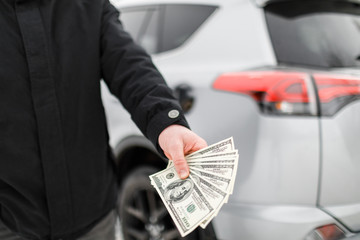 Man with money near car. Money dollars in car fuel tank.