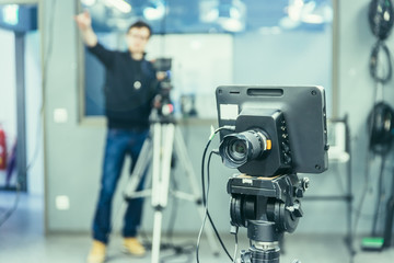 Film camera in broadcasting studio, spotlights and other equipment, cameraman in the blurry background
