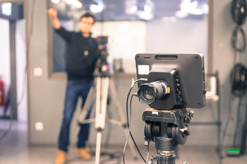 Film camera in broadcasting studio, spotlights and other equipment, cameraman in the blurry background