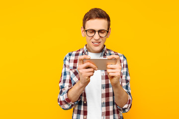 Man playing the phone on a yellow background