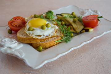 Dried egg on toast bread, eggplant, tomatoes and green peas as breakfast on white plate