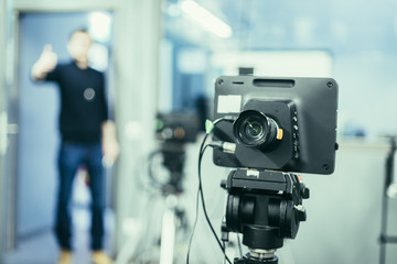 Film camera in broadcasting studio, spotlights and equpiment, director in the background