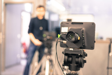 Film camera in broadcasting studio, spotlights and equipment, cameraman in the blurry background