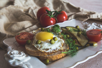 Dried egg on toast bread, eggplant, tomatoes and green peas as breakfast on white plate