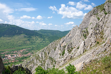 Sunny summer day at mountain peak, where tourists climb to conquer fear, find courage and develop lateral thinking skills to overcome difficulty of climbing a mountain. Small road with rolling stones 