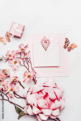 Stylish greeting card mock up with flowers, ribbon, little gift box and hearts in coral color on white background, top view. Wedding,Mothers day , birthday or abstract love concept. Flat lay. Blog