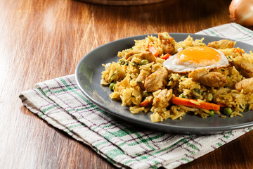 Fried rice nasi goreng with chicken egg and vegetables on a plate.