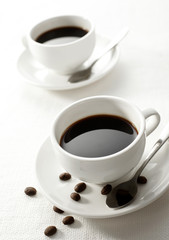 Two cups white tablecloth, with a little coffee beans
