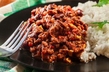 Hot chili con carne with ground beef, beans, tomatoes and corn served with rice