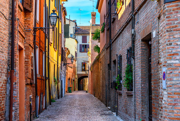 Fototapeta na wymiar Old narrow street with arch in Ferrara, Italy. Ferrara is capital of the Province of Ferrara