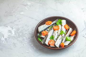 Sardines or baltic herring with rosemary, thyme, parsley,  tomatoes slices and spaces