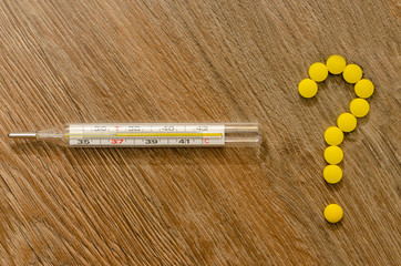 Question mark from tablets and thermometer on wood background